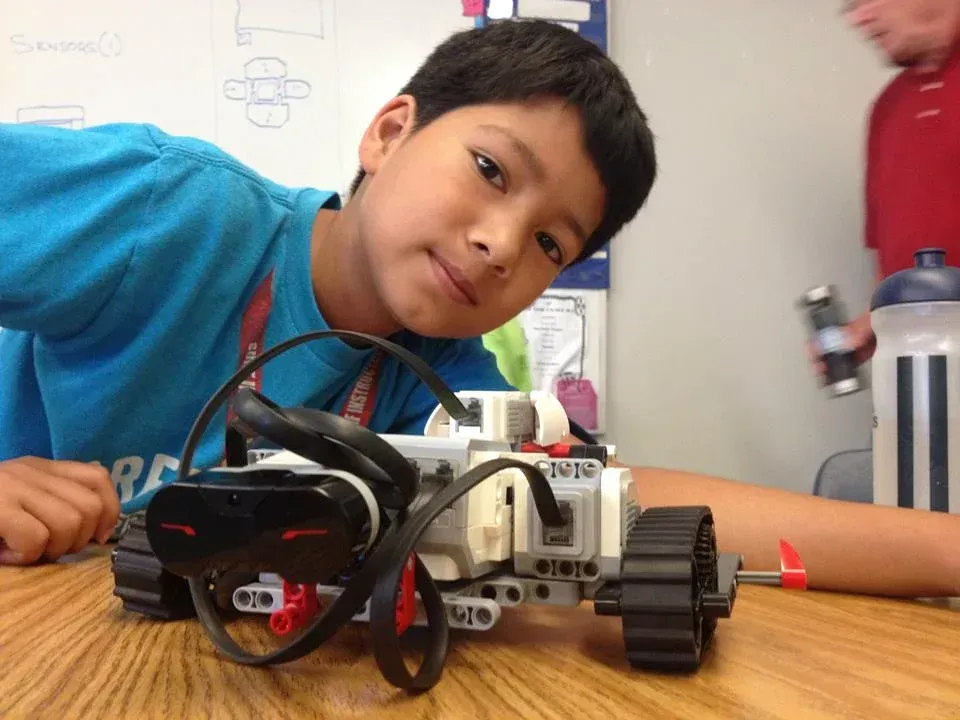 A boy in a blue shirt is working on a robot