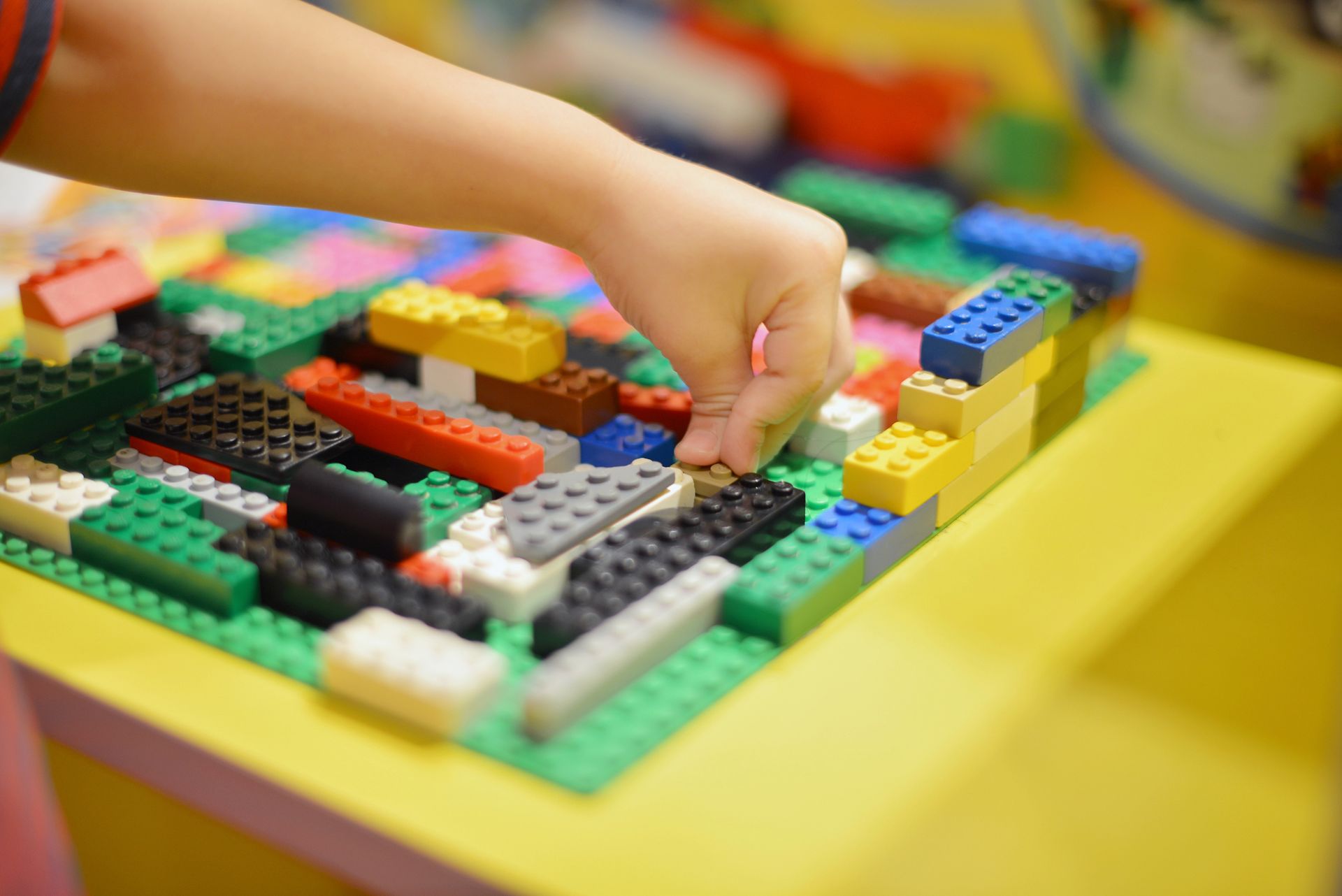 A child is playing with lego blocks on a table.