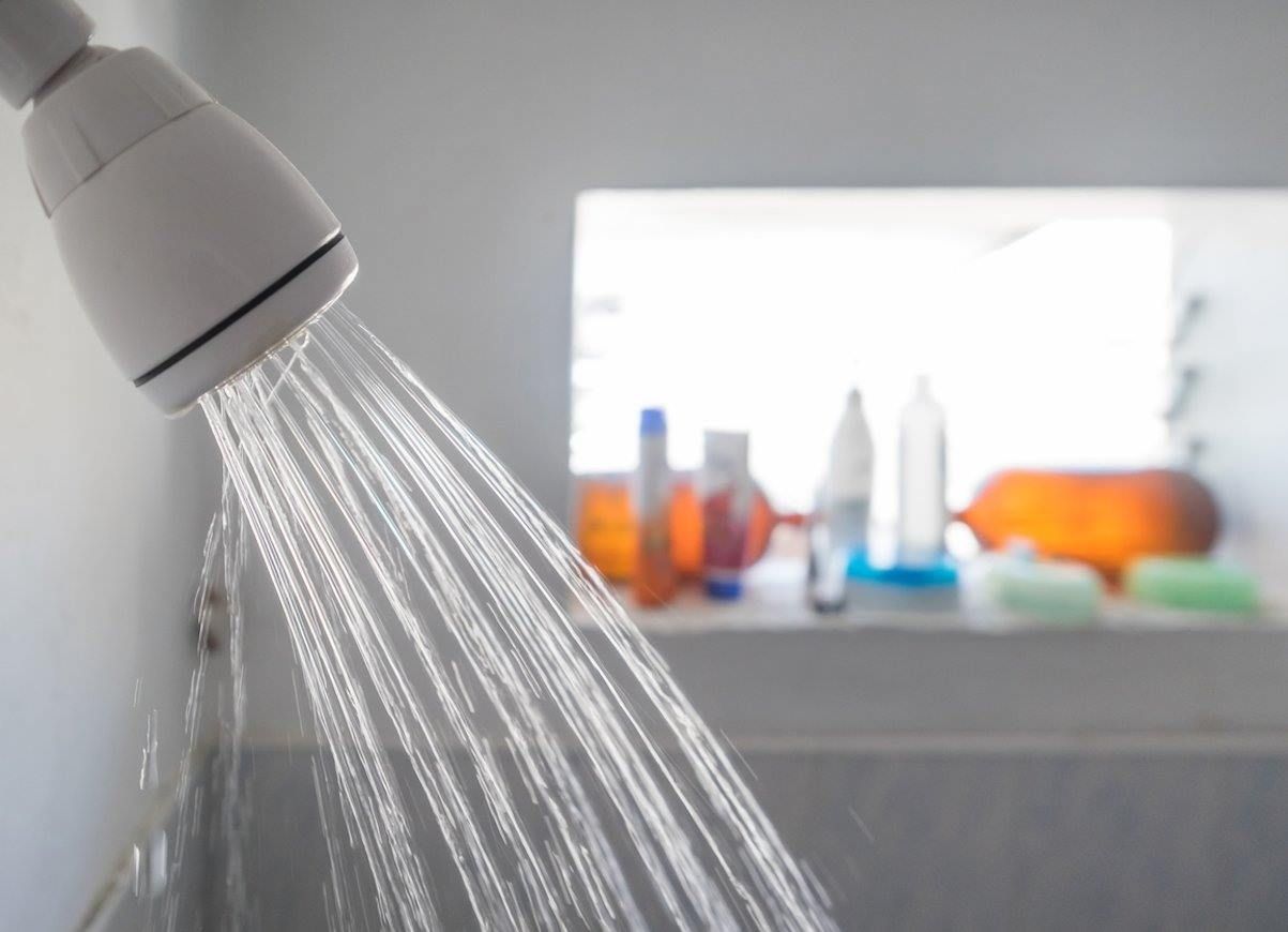 A shower head with water coming out of it in a bathroom