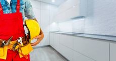A construction worker is holding a hard hat in a kitchen.
