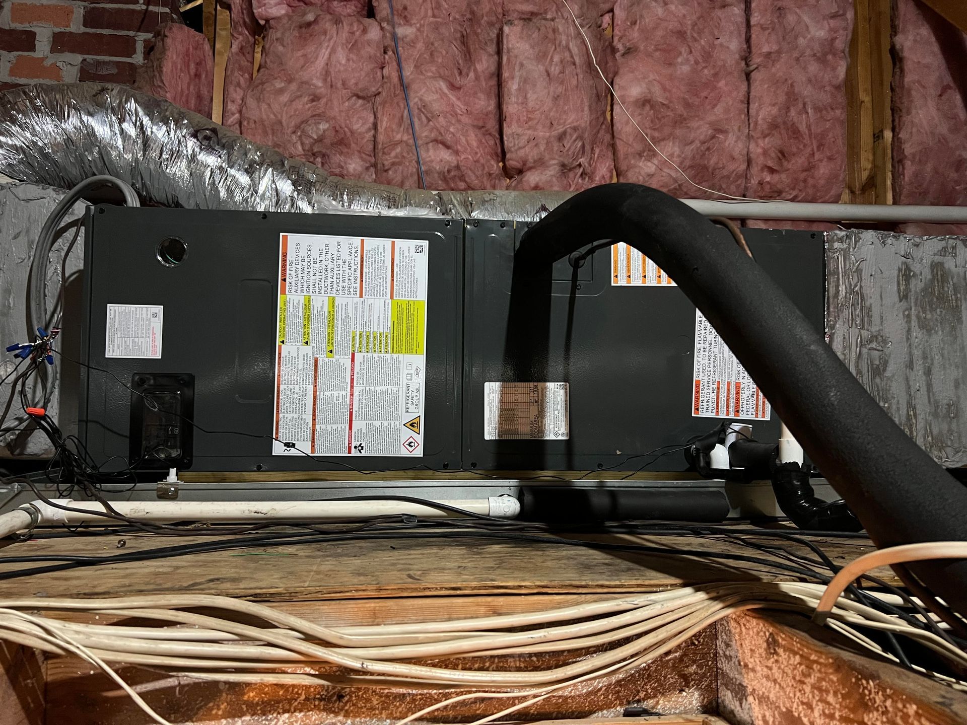 HVAC unit in an attic with insulated ductwork and electrical wiring.