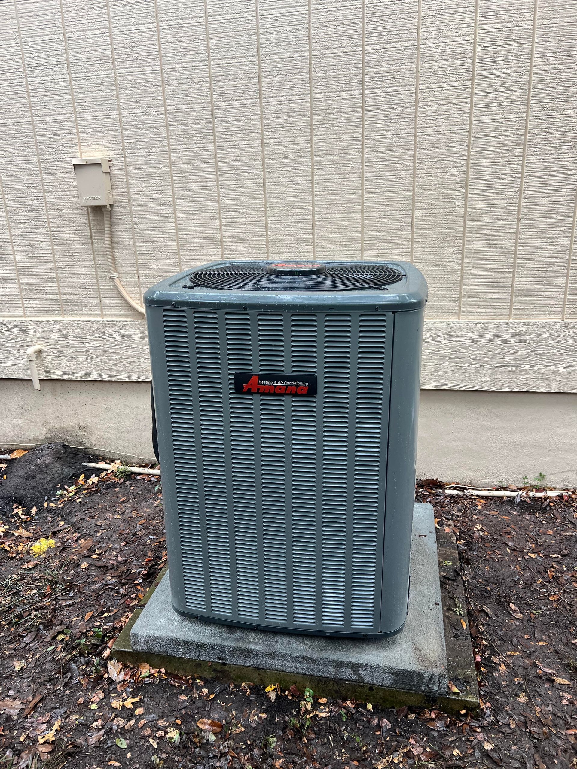 Gray air conditioning unit outside a textured building.