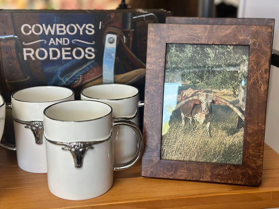 Shop window display filled with colorful ceramic plates, vases, and small trinkets, lit from above at night.