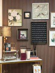 Wall displaying frames, wall art, candles, signs, and decorative items in a store.