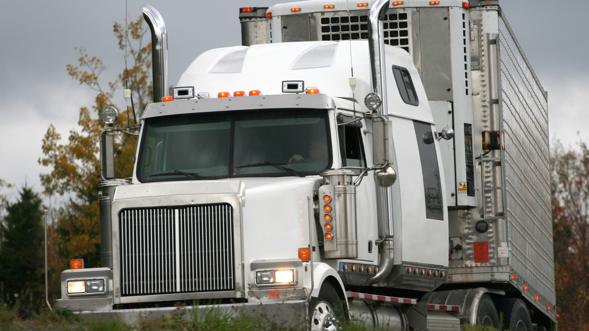 A semi truck with a trailer attached to it is driving down a road.