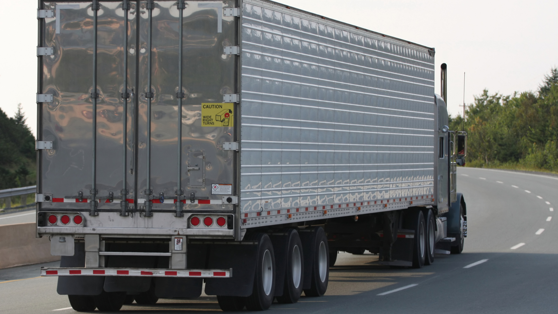 A semi truck is driving down a highway.