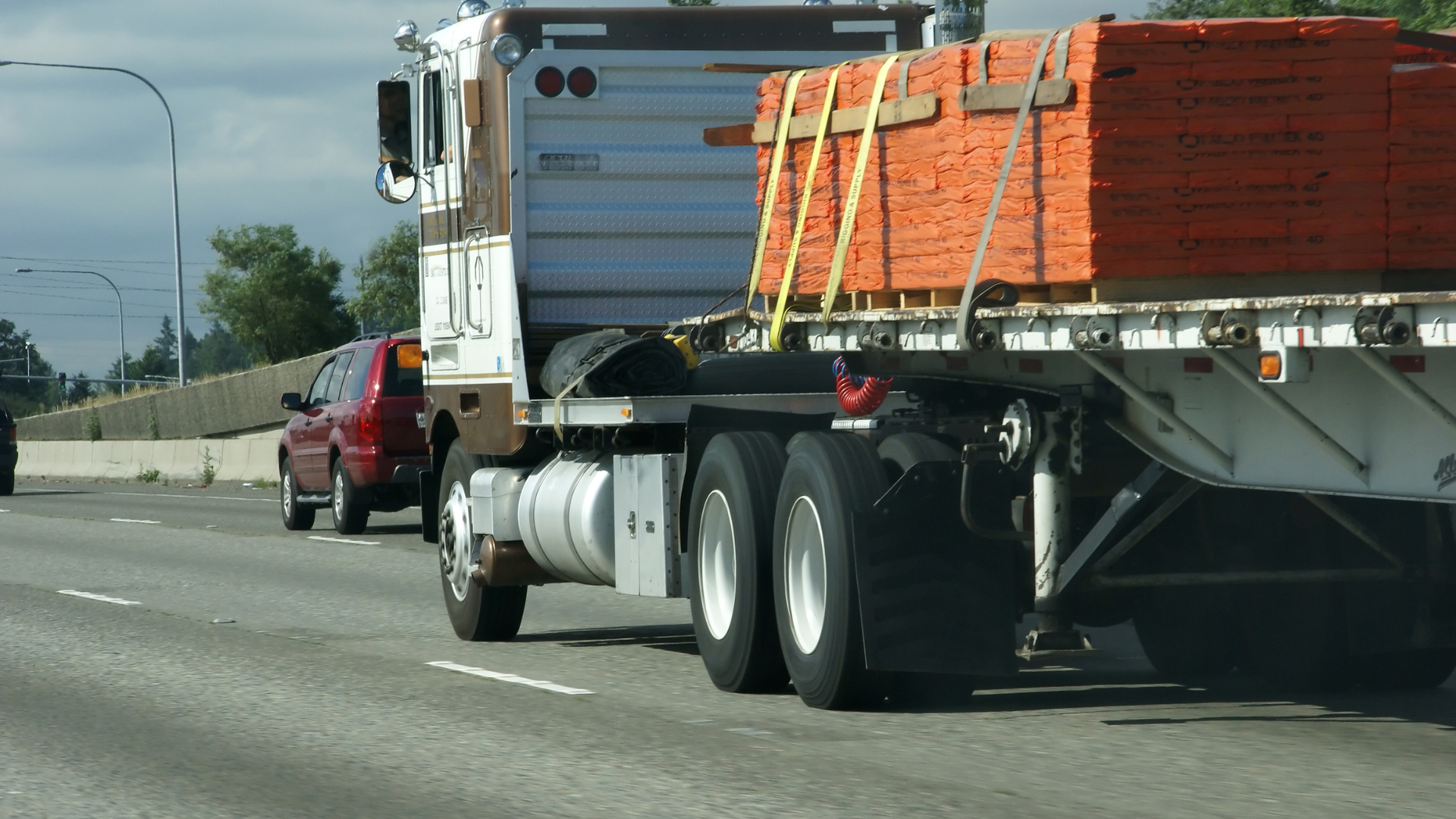 A semi truck with bricks on the back is driving down a highway