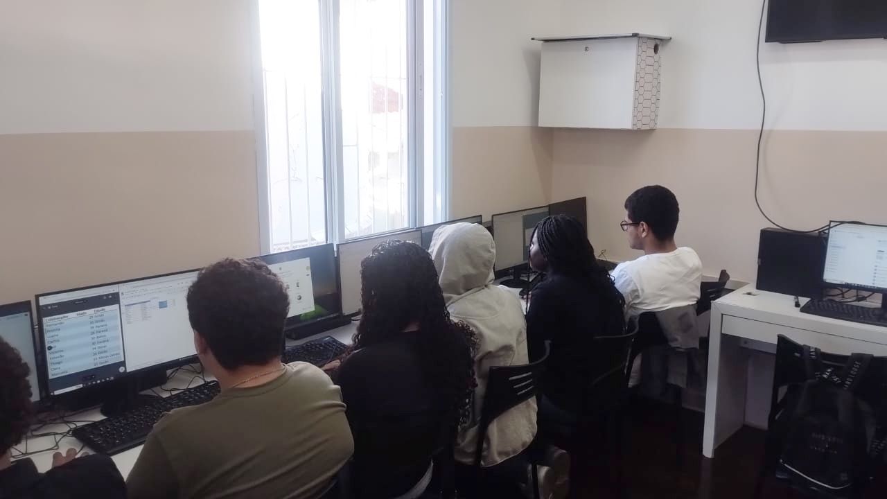 Uma pessoa está sentada em uma mesa escrevendo em um pedaço de papel com uma caneta.