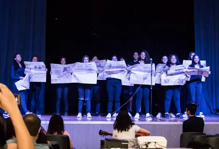 Um grupo de pessoas está em um palco segurando cartazes.