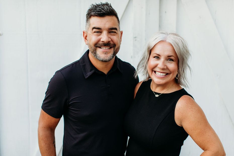 Smiling couple indoors, woman in rust-colored top, man in tan polo.