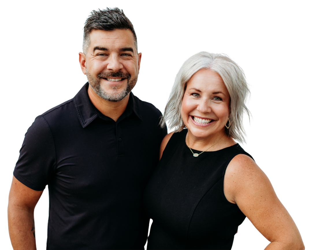 Smiling couple posing together, man with dark hair, woman with silver hair, both in black.
