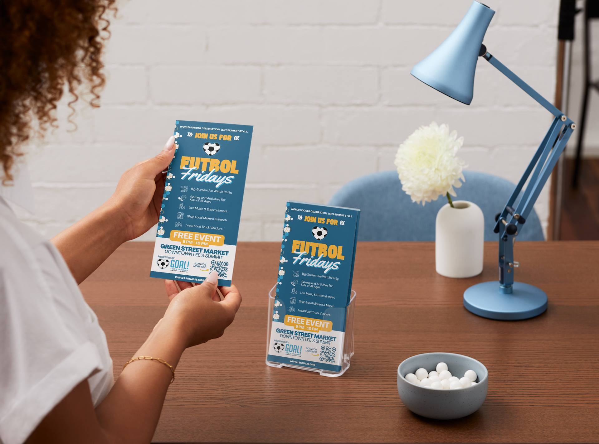 Woman working at a desk with a computer and laptop, editing a website.