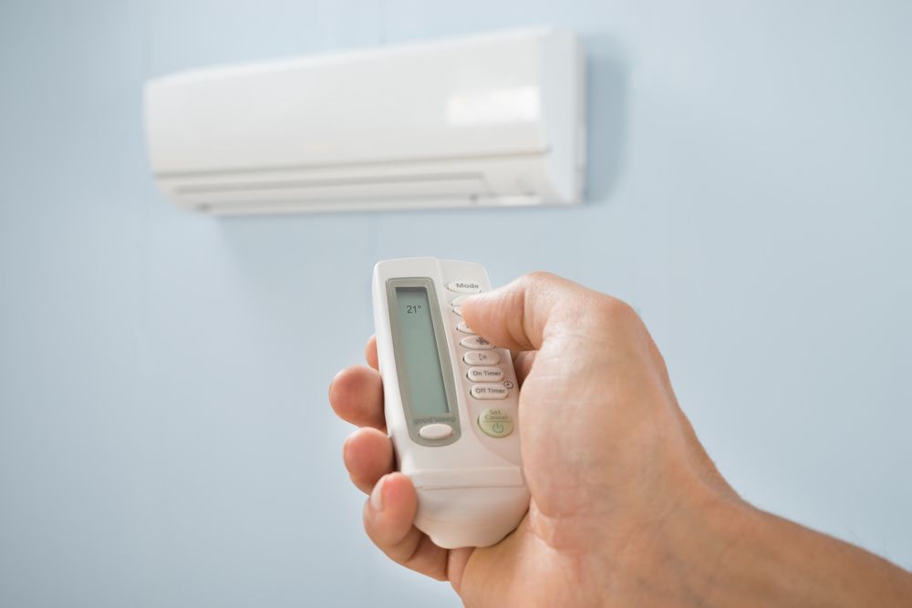 Hand Holding Ac Remote  — RedJak Air Conditioning Services in Ipswich, QLD