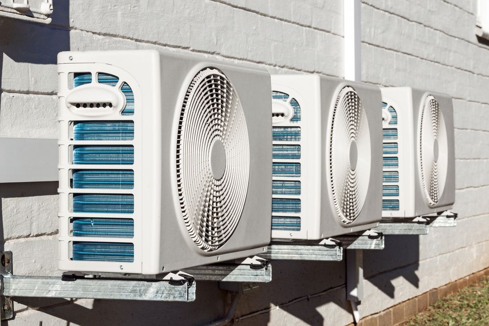 Row of Outdoor Air Conditioning Units Mounted on A Building Wall — RedJak Air Conditioning Services in Willawong, QLD