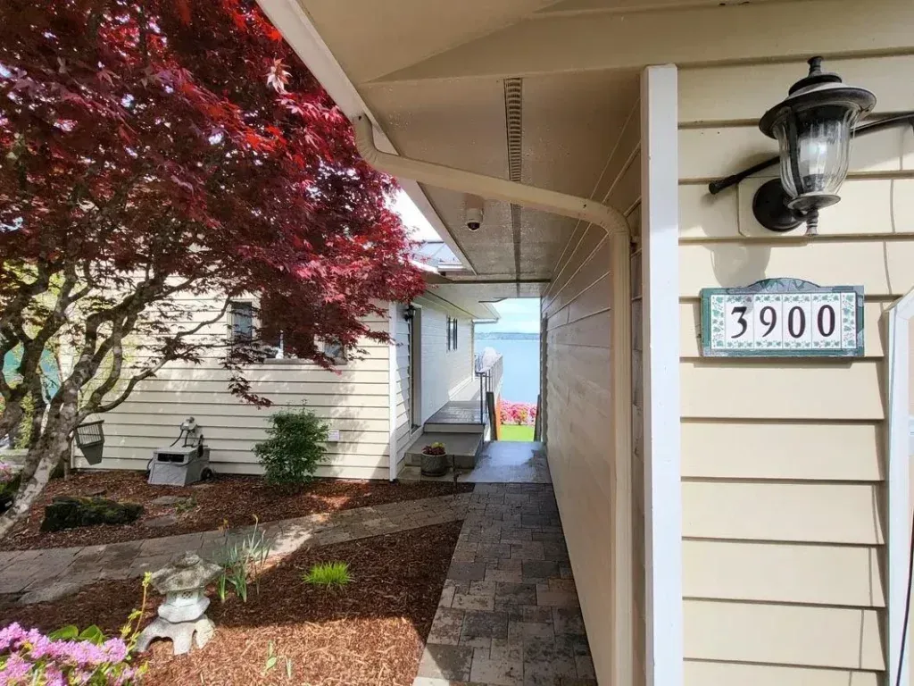 House entryway with beige siding, a red-leaf tree, and address plaque 3900