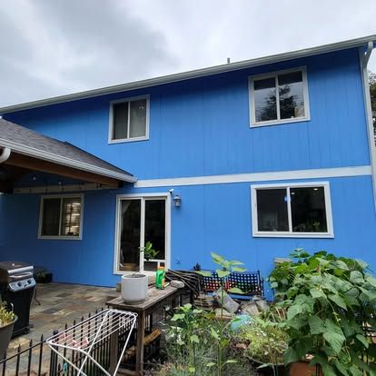 Blue two-story house with white trim and a small patio garden in front