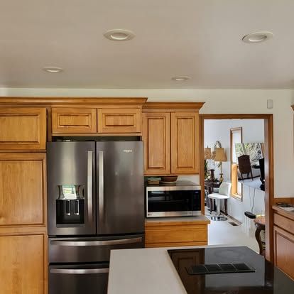 Modern kitchen with stainless steel appliances, wood cabinets, and a view into another room
