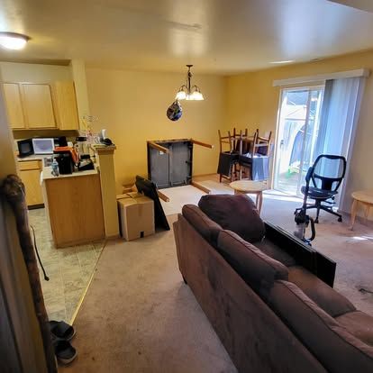 Small apartment living room with brown couch, kitchen area, and sliding glass door to a patio.