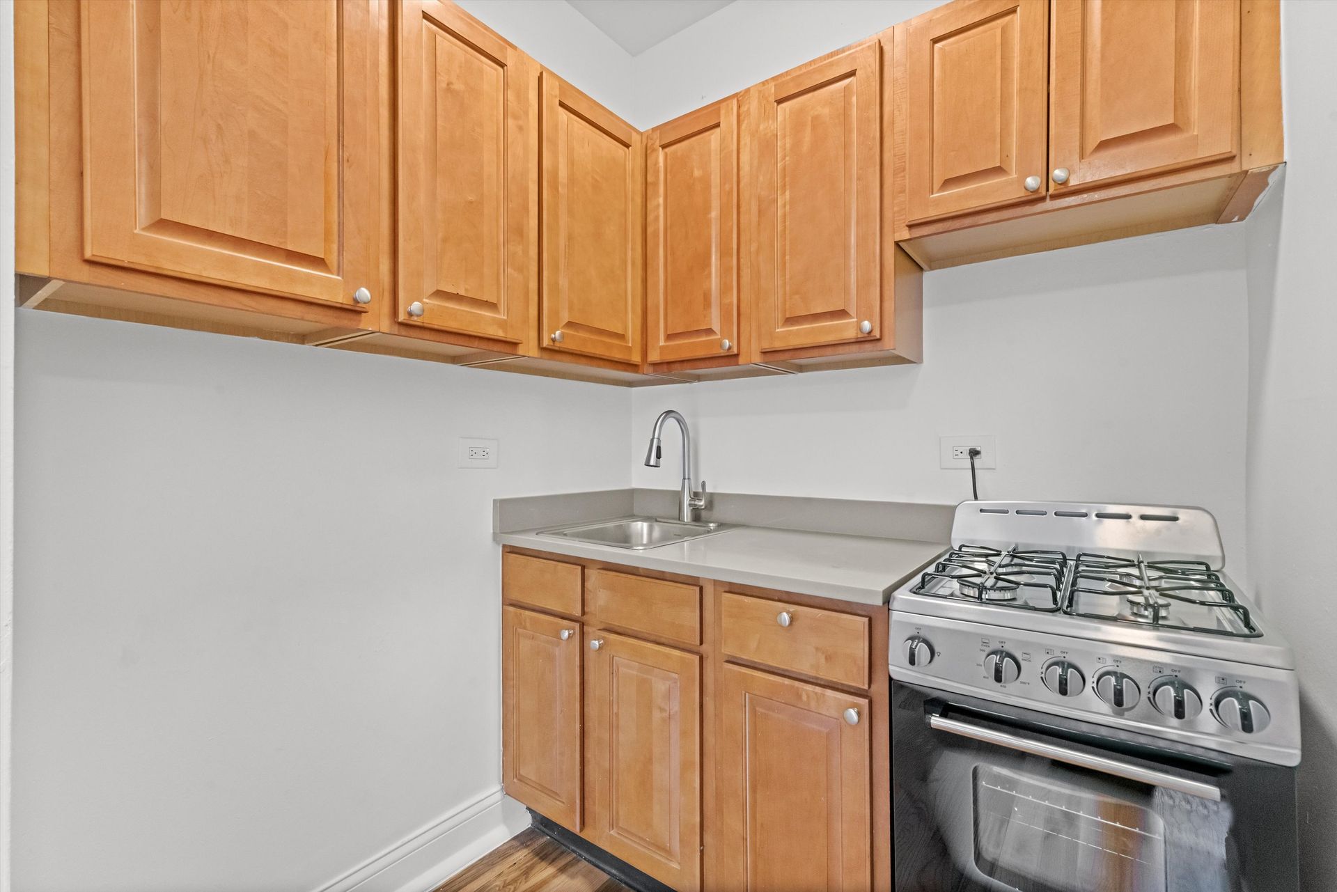 Small kitchen with wooden cabinets, a stainless steel stove, and a sink.