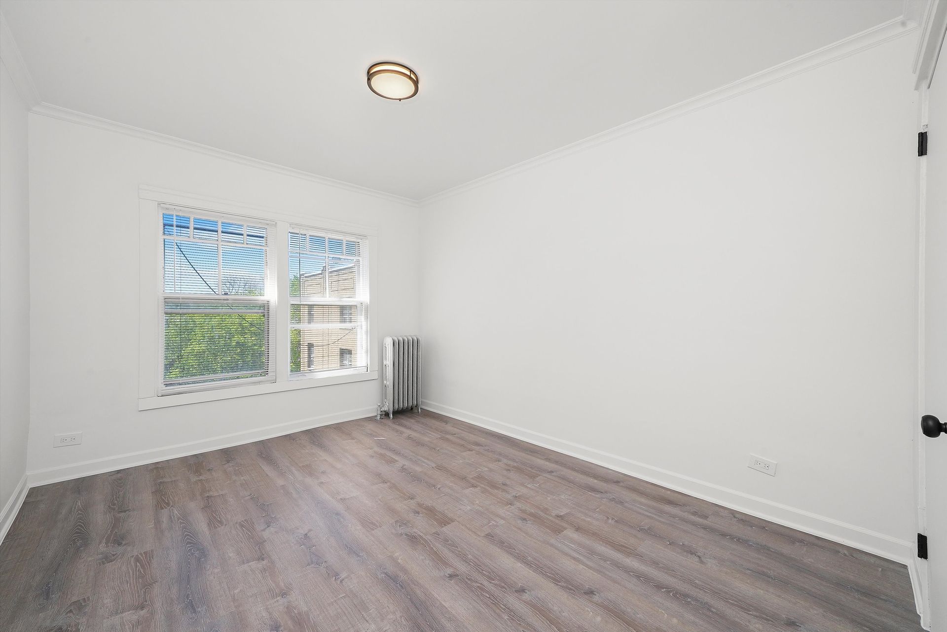 Empty room with white walls, gray wood floor, and a window.