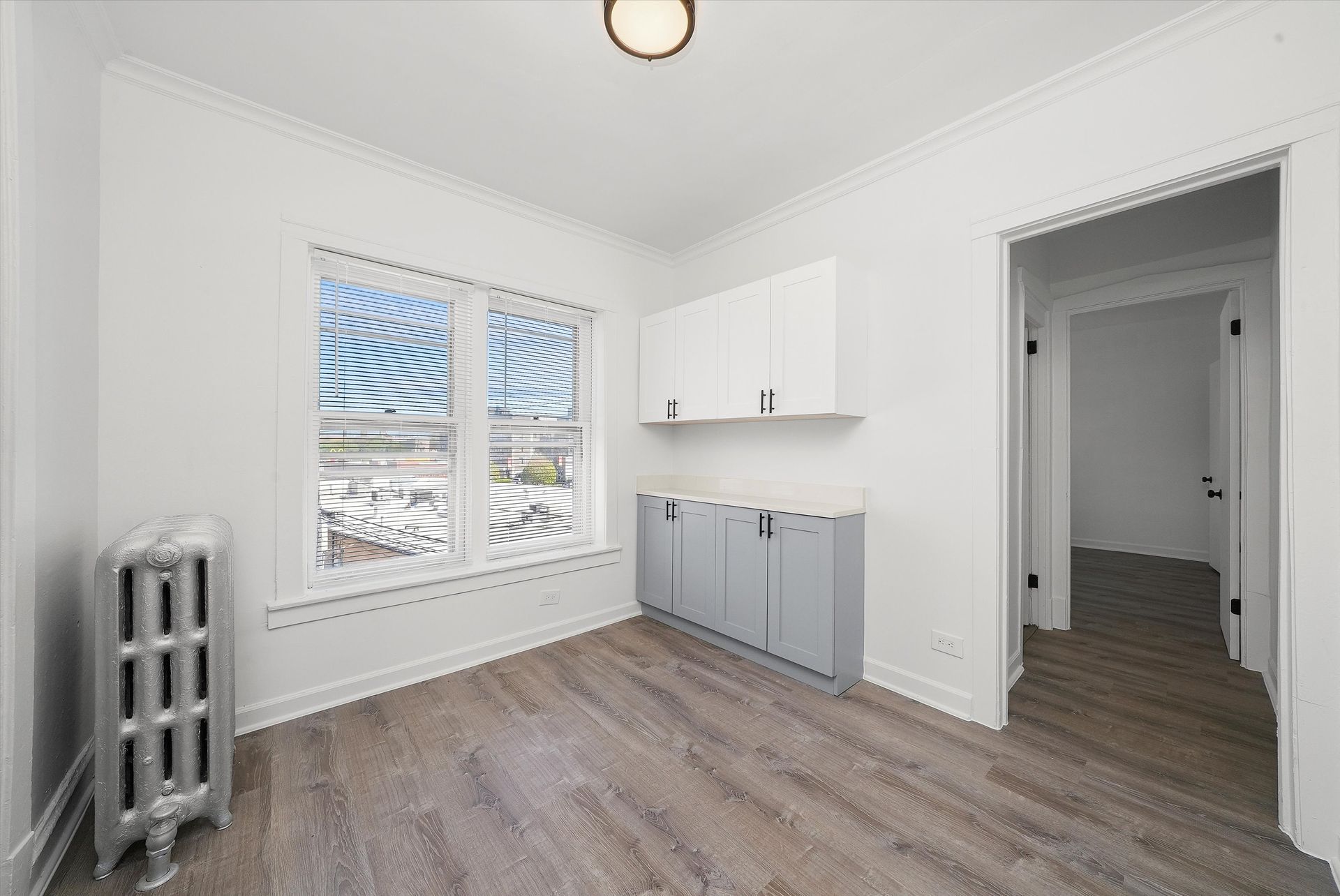 Empty room with gray cabinets, window, and radiator.