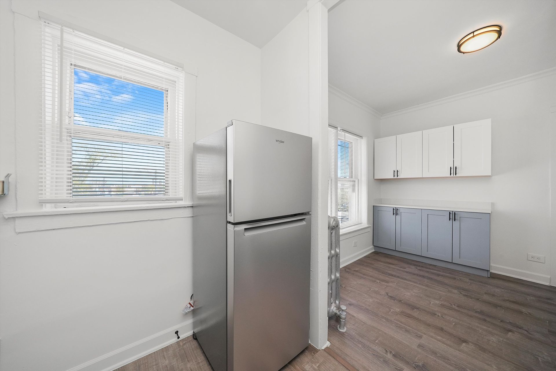 Small kitchen with a stainless steel refrigerator, window, and cabinets.