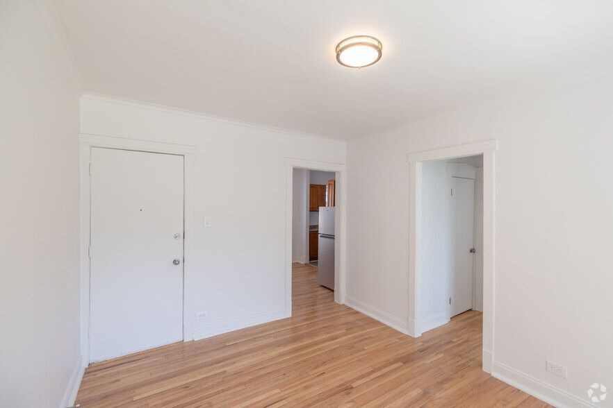 Empty, bright room with hardwood floors, white walls, and two doorways.