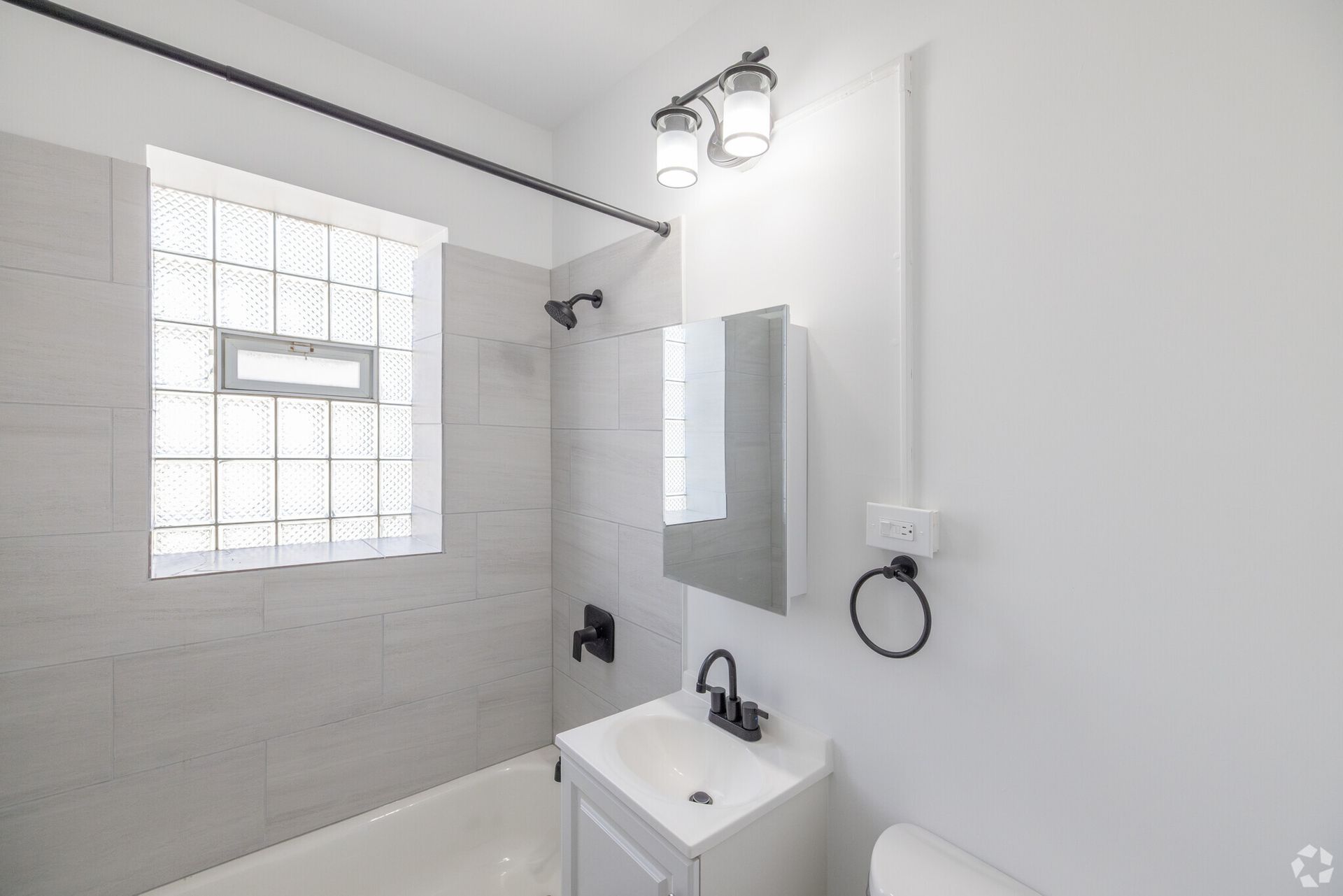 Modern bathroom with white walls, shower, and vanity; black fixtures.