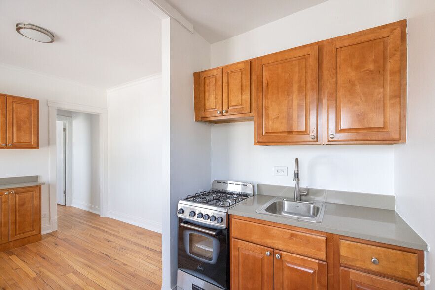 Small kitchen with wood cabinets, a stove, sink, and light gray countertop.