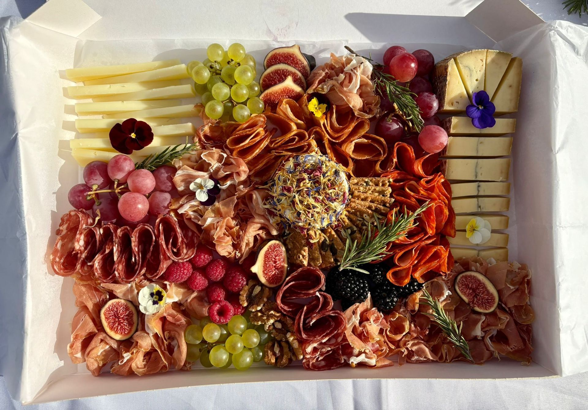 Un coffret petit-déjeuner contenant des crêpes, un gâteau aux graines de pavot, des croissants, des gaufres aux fruits et des baies fraîches.