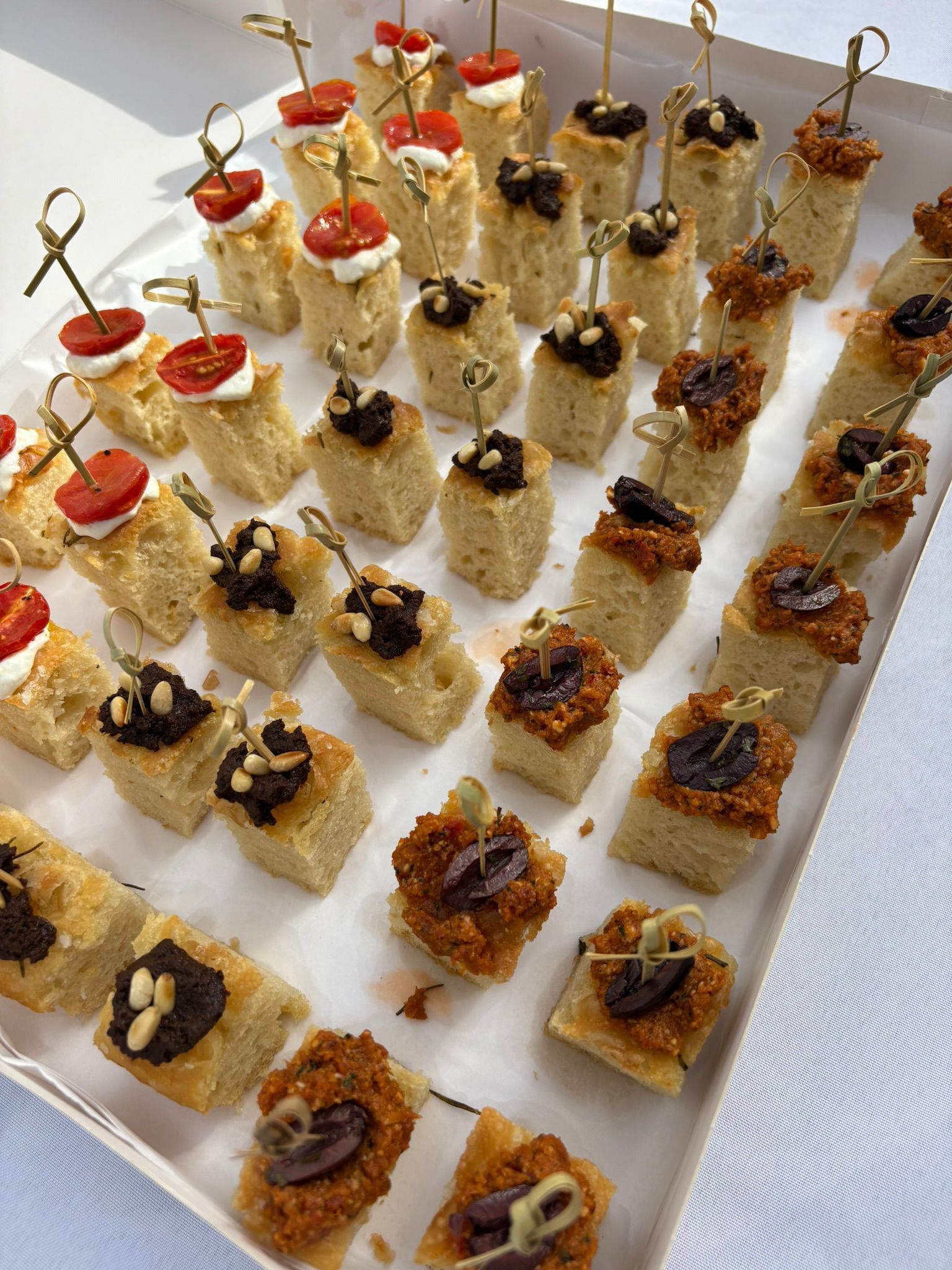 Un plateau de cornets en papier brun remplis d'amuse-gueules assortis, chacun marqué d'un petit drapeau de marque sur un pic vert.