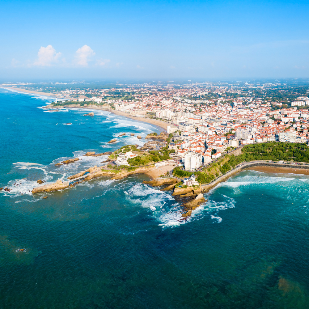 Vue aérienne de la ville côtière de Biarritz, en France, avec ses promontoires rocheux, ses plages de sable et ses bâtiments blancs.
