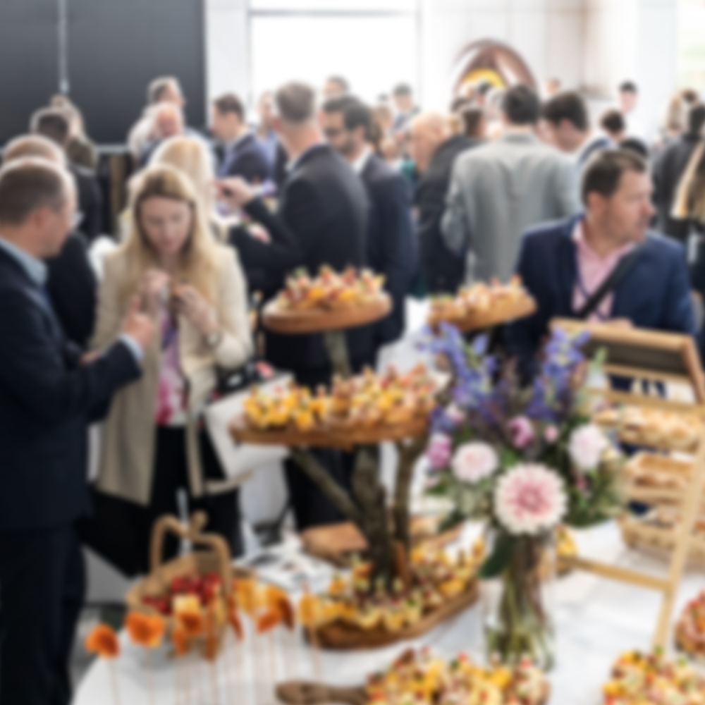 Événement de réseautage professionnel où les participants échangent autour d'une table décorée de plats et de fleurs.