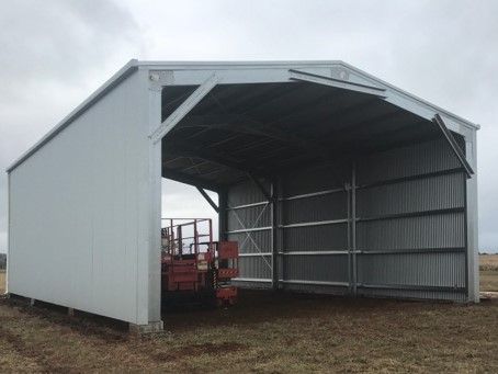 A large white shed with a tractor inside of it.