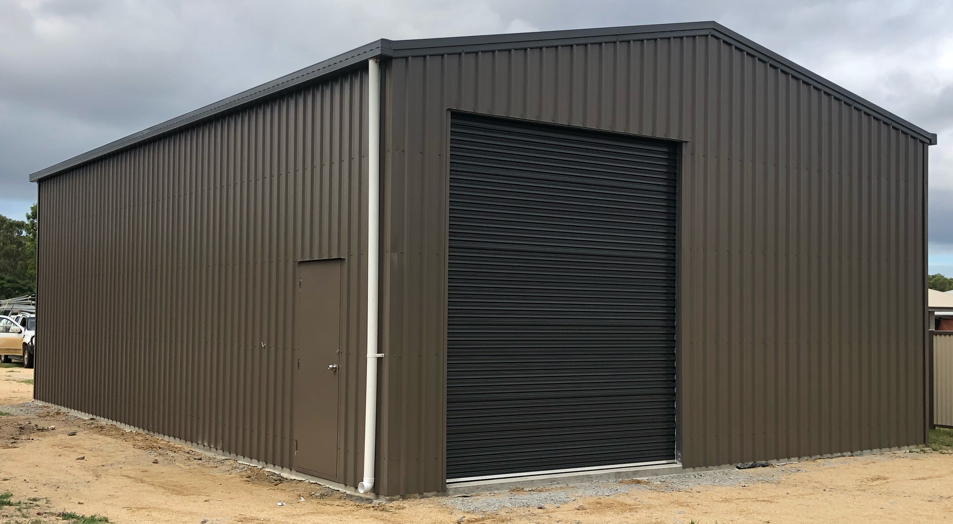 A large brown metal building with a black garage door.