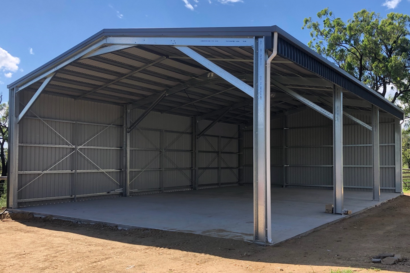 A large metal building is sitting on top of a dirt field.