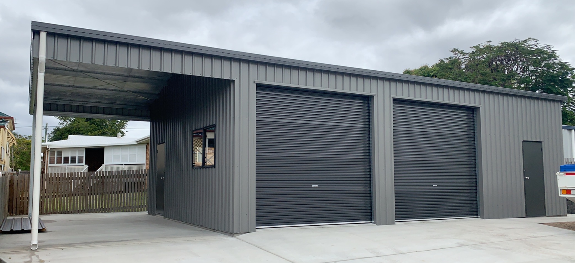 A gray garage with three garage doors and a canopy.