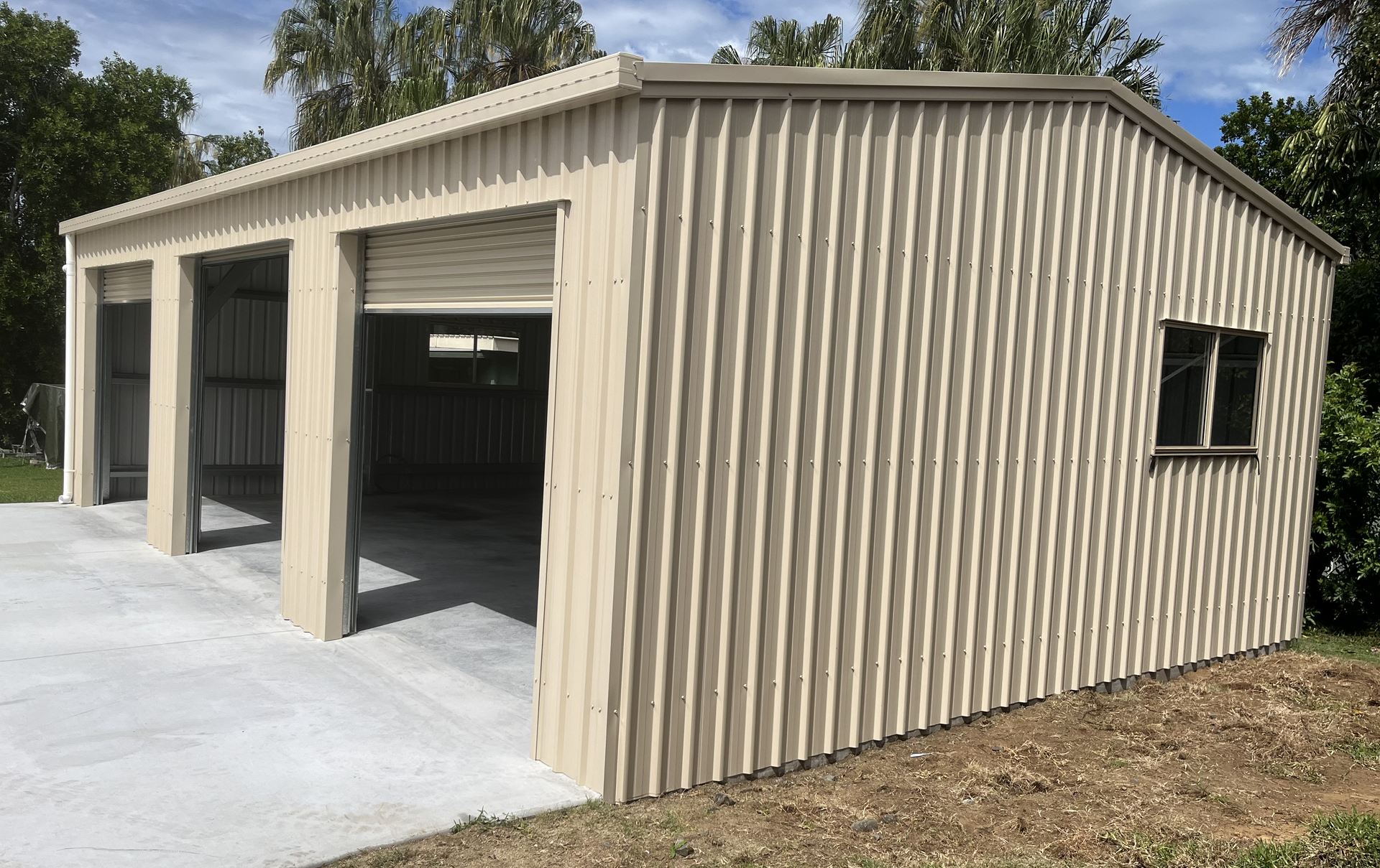 A large metal garage with three doors and two windows