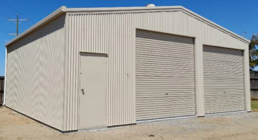 A large white building with two garage doors and a door.