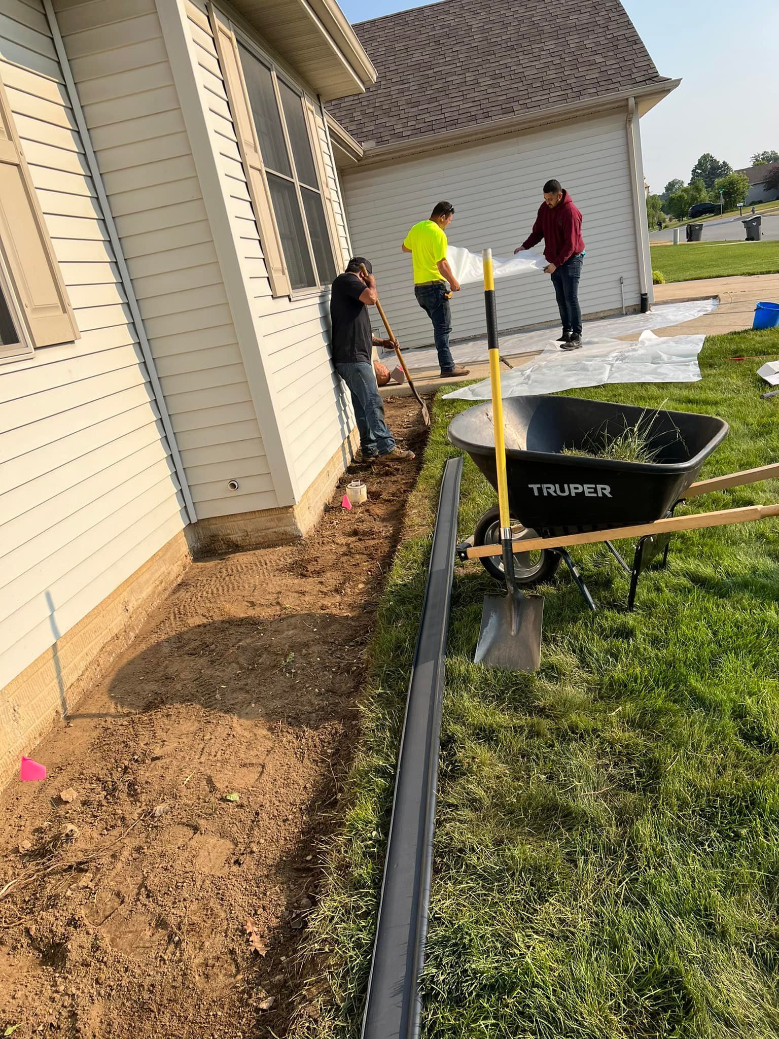 A group of men are working on a sidewalk in front of a house.