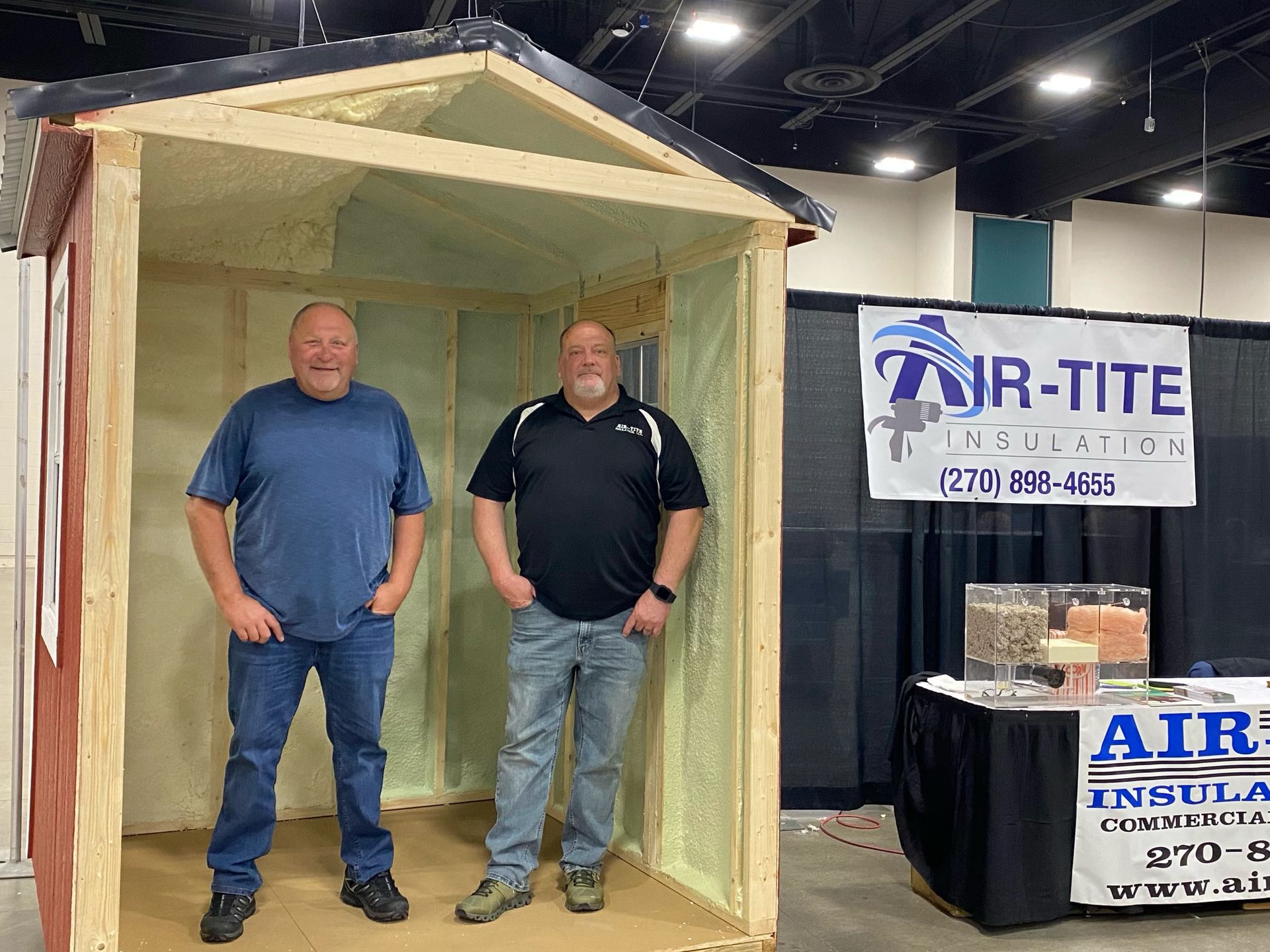 Construction site with several AIR-TITE trucks, partially built houses under a blue sky.