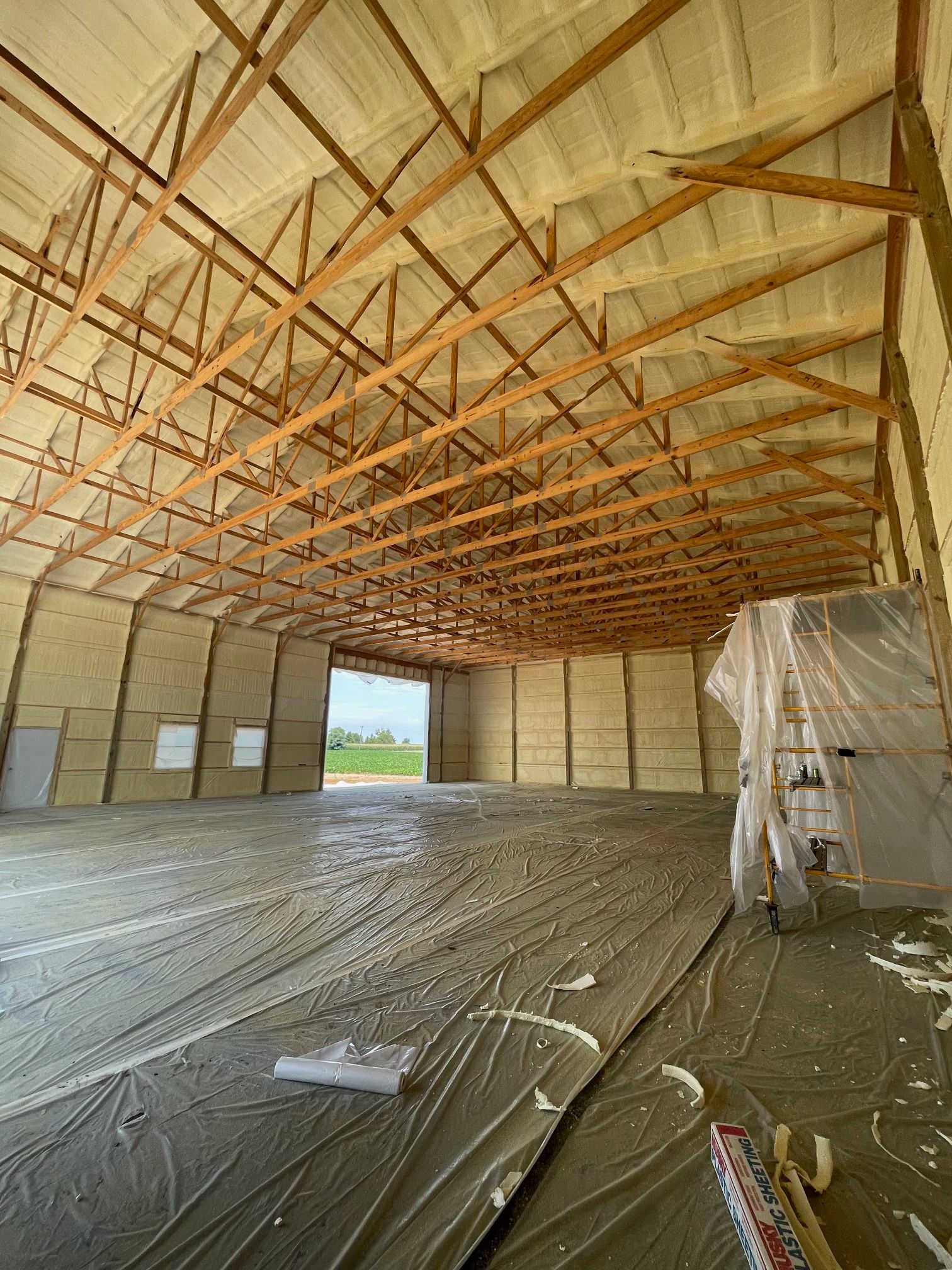 Pool equipment room with black filter, white pipes, and blue siding. Walls are insulated with beige foam.