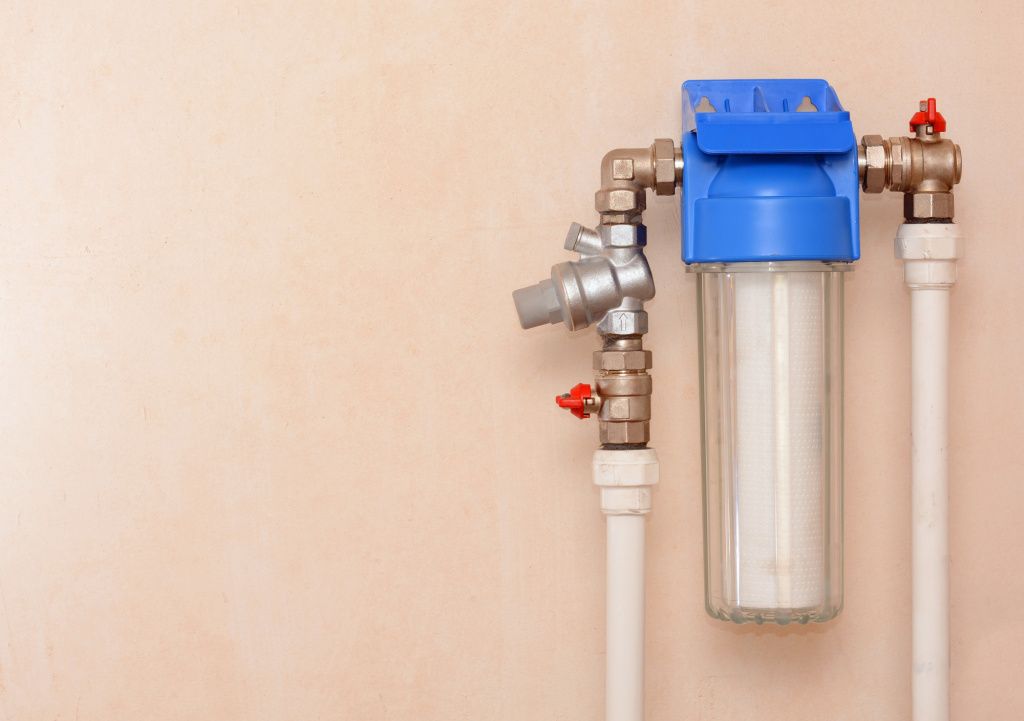 A water filter is attached to a pipe on a wall.