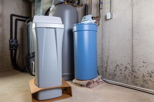 A water softener and a water heater are in a basement.