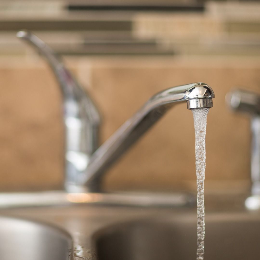A close up of a kitchen sink with water running from the faucet
