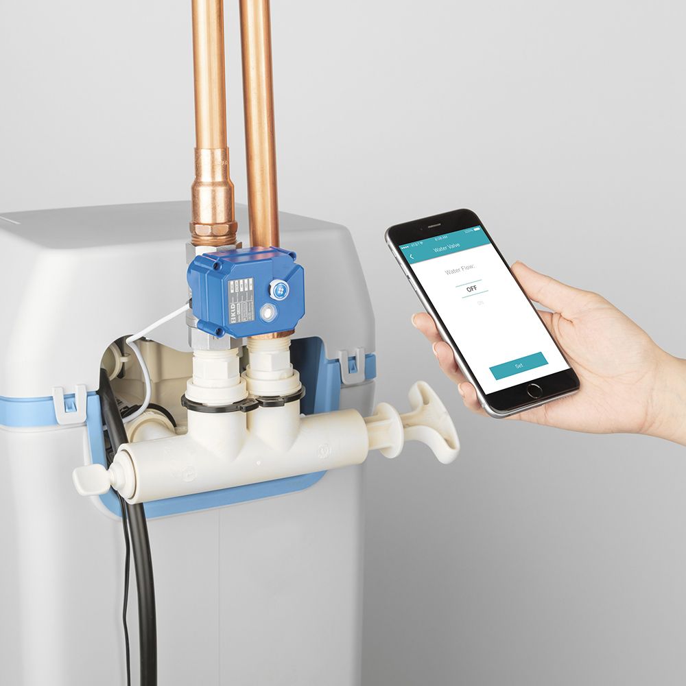 A person is holding a cell phone next to a water filter.