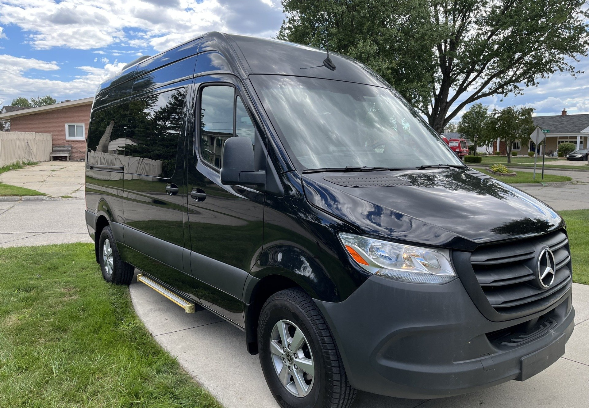 A black mercedes benz sprinter van is parked in front of a house.