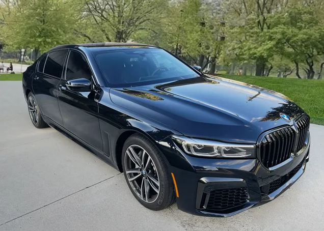 A black bmw 750li is parked in a driveway.