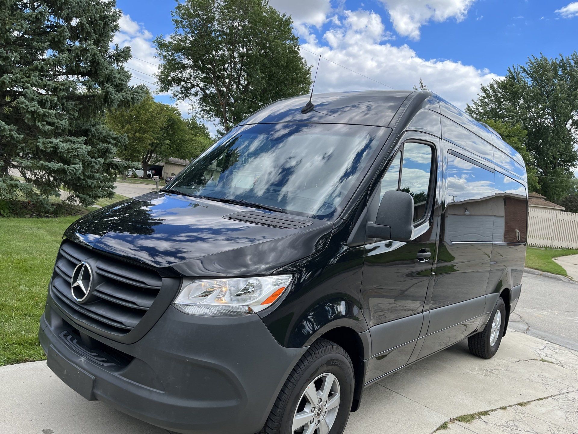 A black mercedes sprinter van is parked in a driveway.