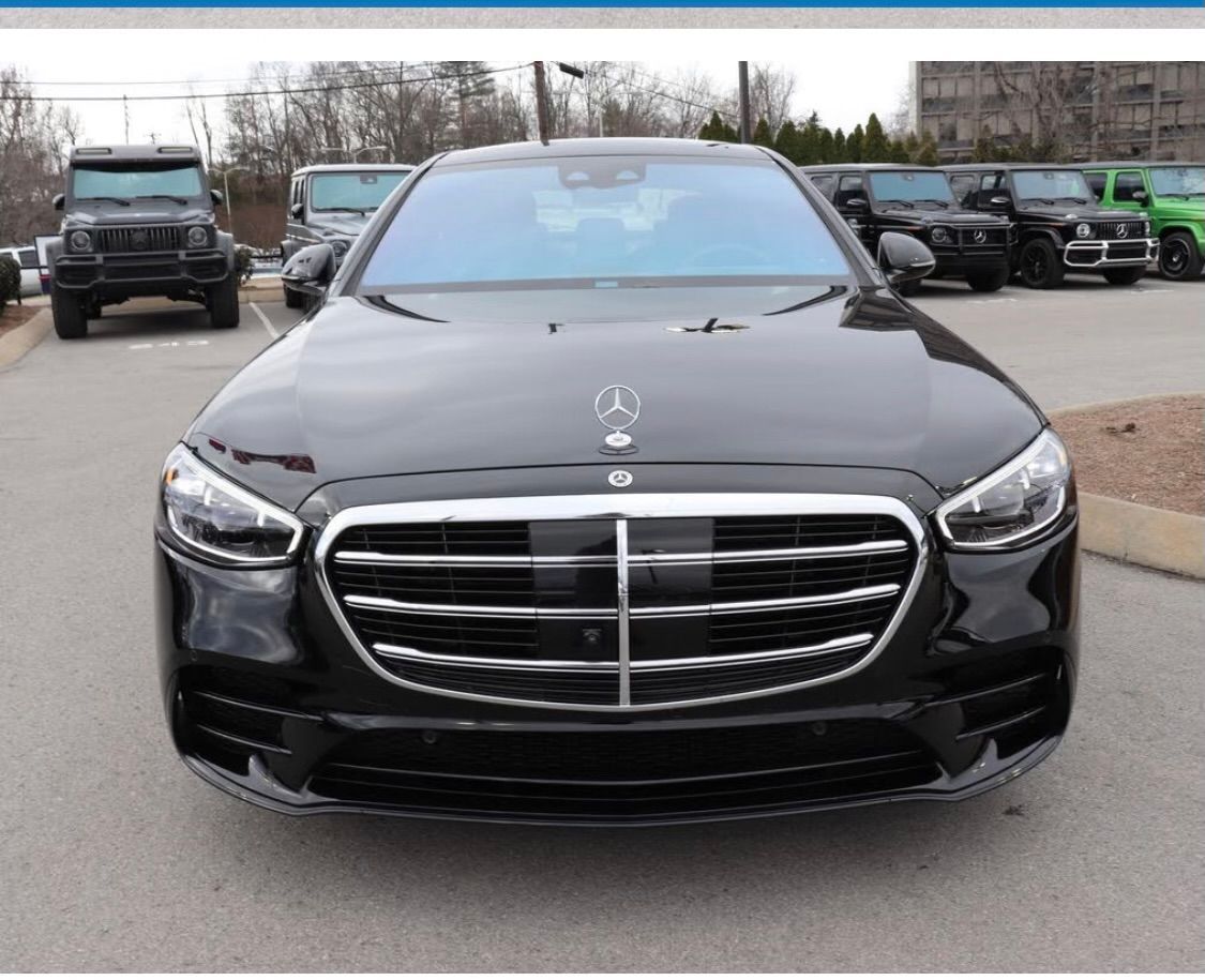 A black mercedes is parked in a parking lot